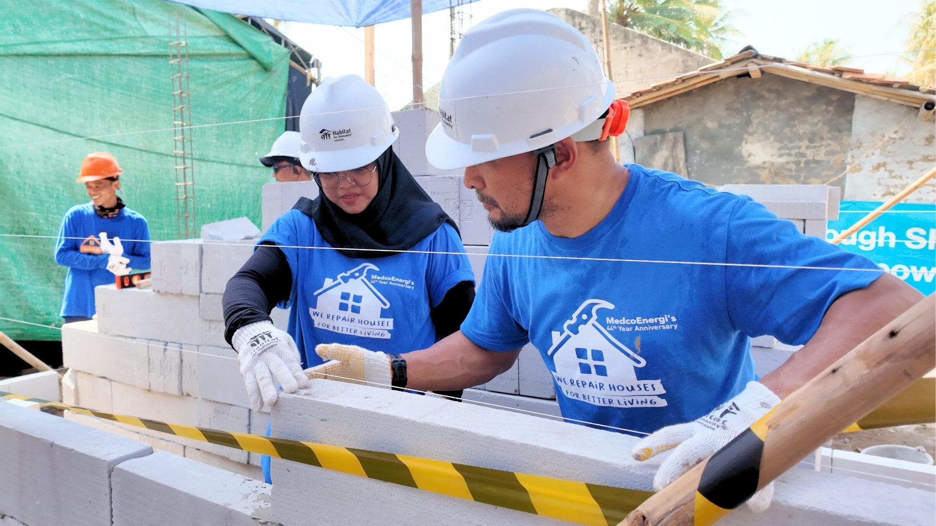 MedcoEnergi volunteers building walls of homes in Marga Mulya Village.