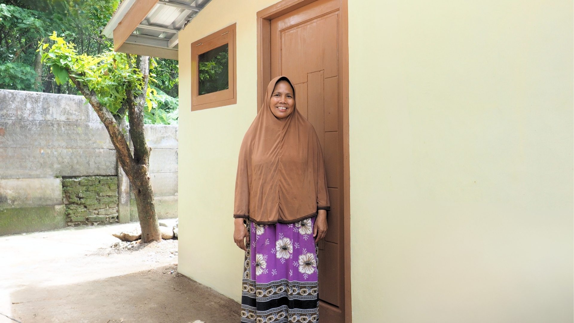 Nunung standing happily in her newly renovated kitchen, showcasing the transformation.